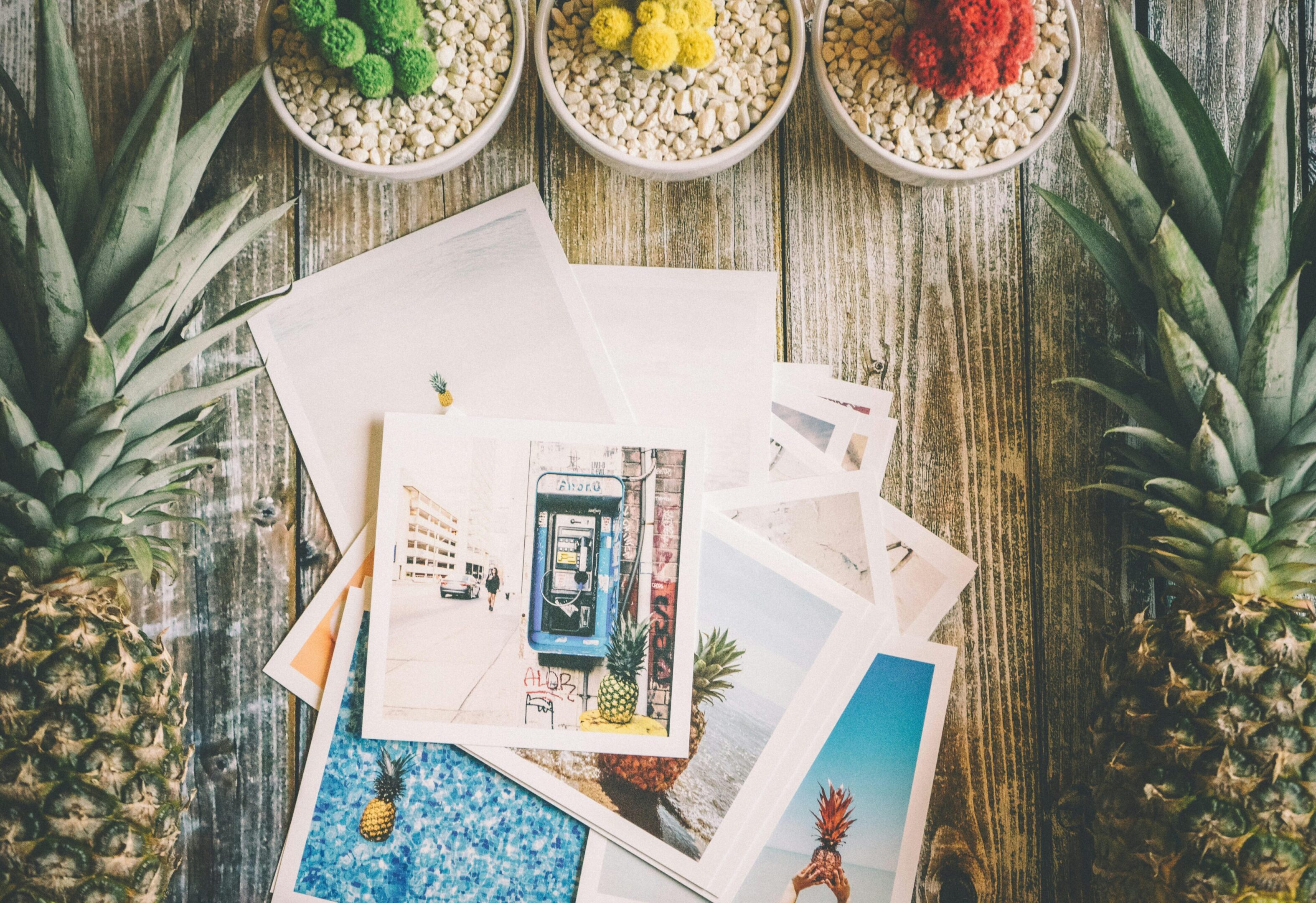 A collection of postcards and colored sand jars on a wooden table.