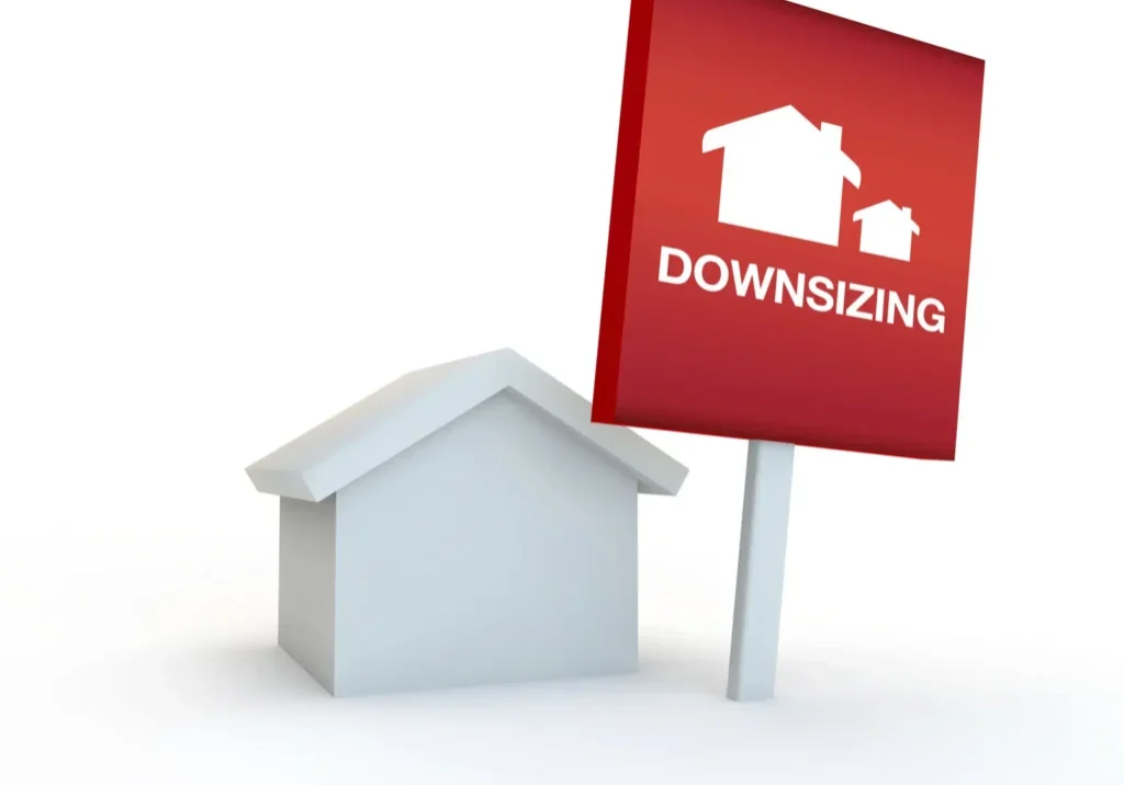 Small house model with a downsizing sign beside it.